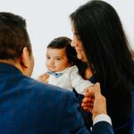 Smiling baby boy held by parents during a cozy studio photography session"